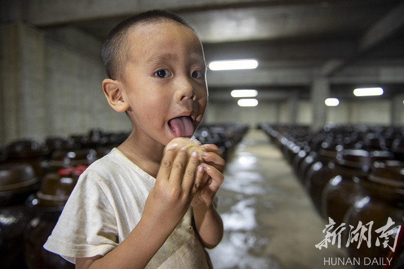 8月21日，永州市冷水滩区麦子园村，小孩子舔吃陶土坛里腌制出来的大蒜。 湖南日报·华声在线记者 辜鹏博 摄
