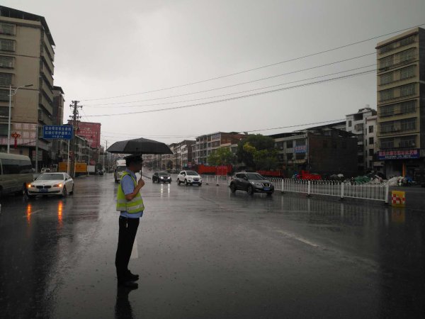  交警在祁东县永昌街道G322线K58+200-K58+700M路段雨中执勤。