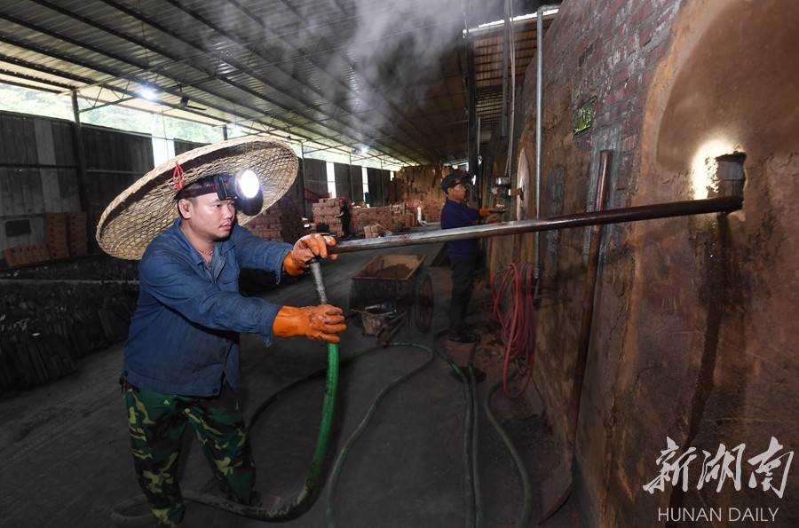 9月26日,炎陵县垄溪乡林龙炭业制品厂生产车间,竹炭烧制完成后,工人给