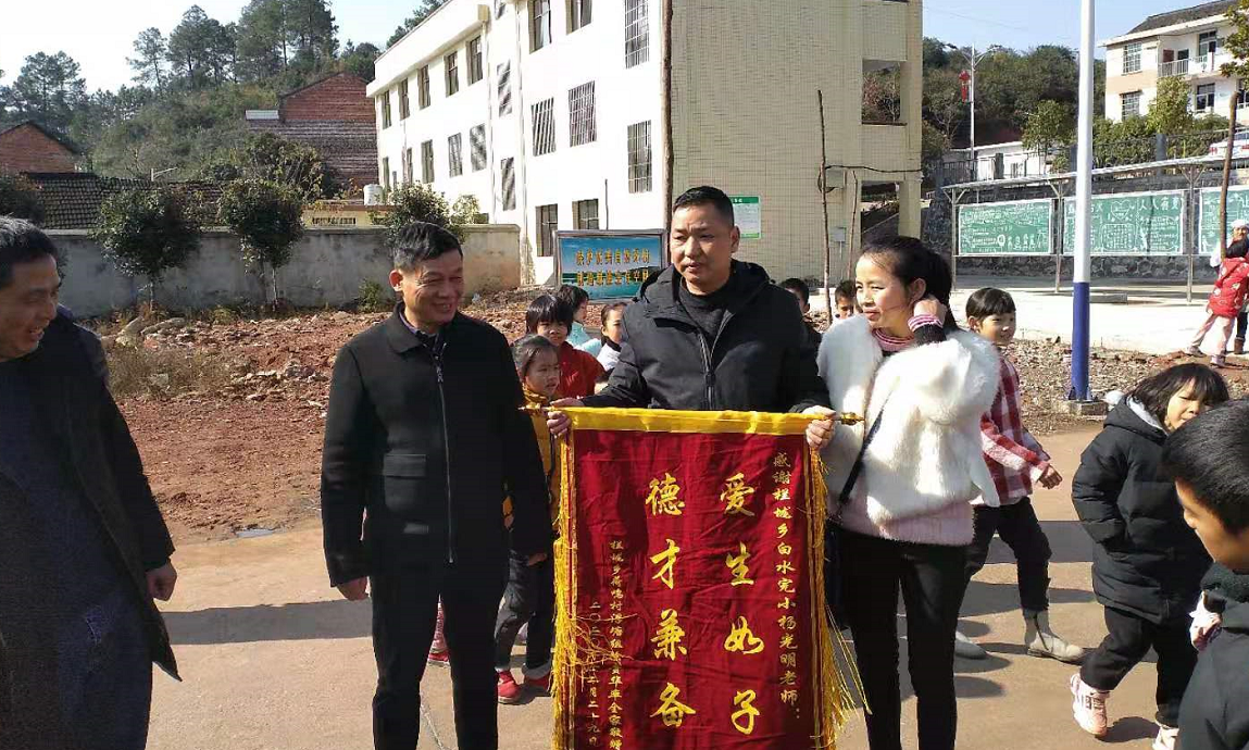 荷鸣村村支两委和小杰父母为杨光明老师送来锦旗。 戴明军摄