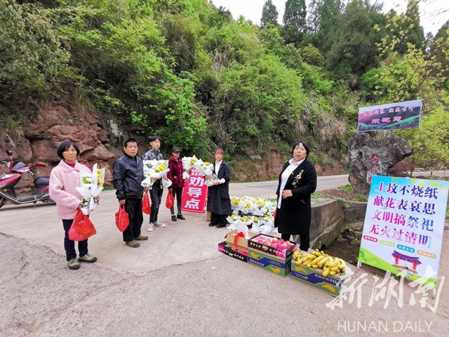 古冲村党总支书记龙四清（右）正在给上山扫墓的村民分发鲜花和祭品。李夏涛 摄