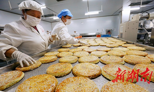 靖州苗族侗族自治县异溪食品厂车间内，糕点师傅们正在加工制作靖州传统“土月饼”。得益于干部的倾力帮扶，该公司早已摆脱入园前销路不畅的困境，如今产销两旺。（靖州县委宣传部供图）