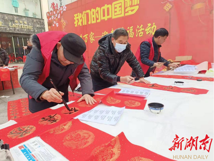  益阳市资阳区文化馆聚友斋书画院书法家在益阳市商业样板街给居民免费写春联。蒋晓涵 摄