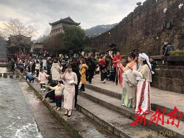 游客们穿者颜色各异、不同款式的苗服、汉服服装在凤凰古城拍照
