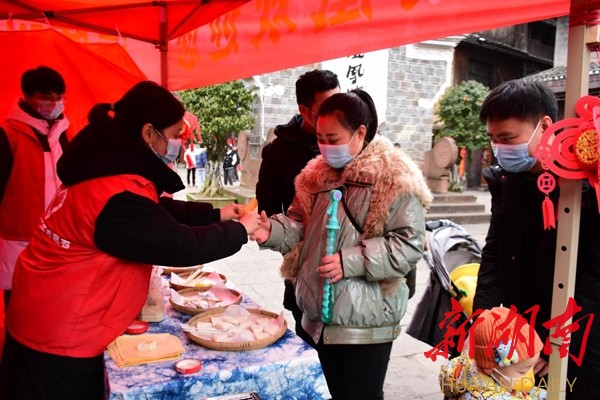 志愿者为游客送上热乎的糍粑。 志愿者为游客送上热乎的糍粑。