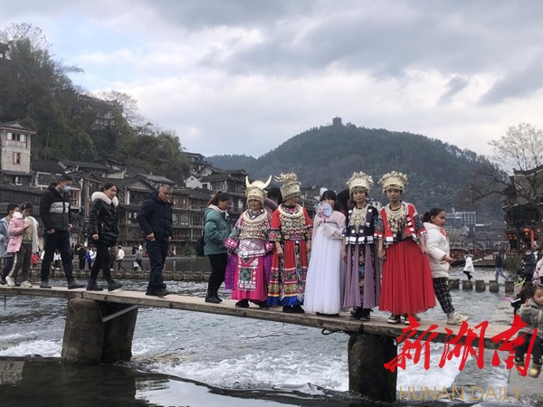 游客们穿者颜色各异、不同款式的苗服、汉服服装在凤凰古城拍照