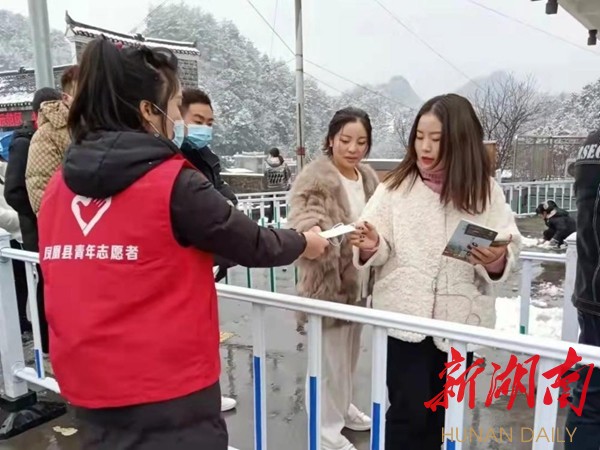 志愿者为游客免费发放口罩。 志愿者为游客免费发放口罩。