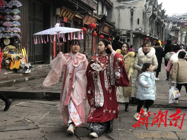 游客们穿者颜色各异、不同款式的苗服、汉服服装在凤凰古城拍照