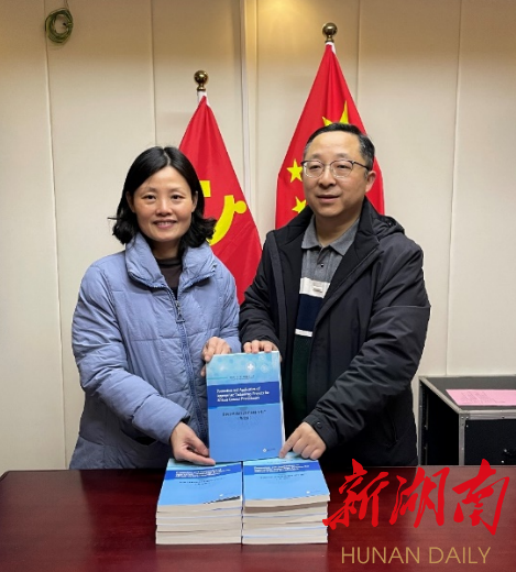 图为梁力晖（右）向第23批援塞拉利昂医疗队队长周曦捐书