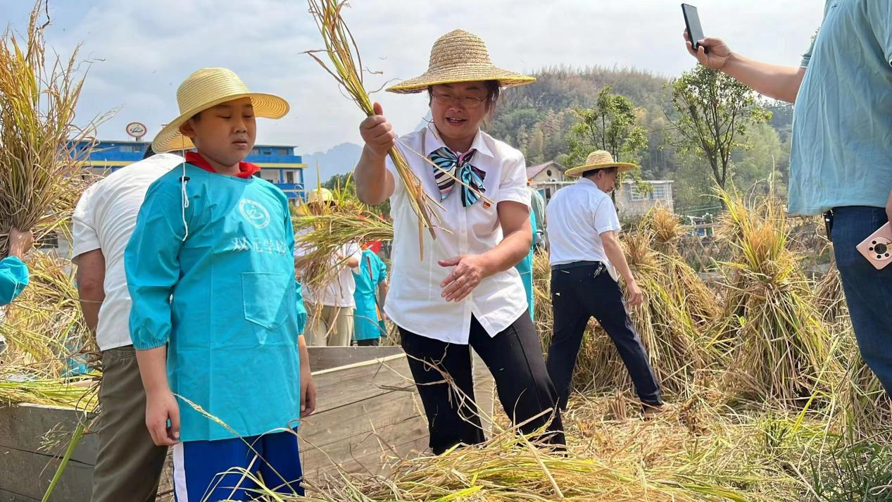 过程,长铺一小校长杨长翠和双元学校校长谭海丽各割下了第一把稻谷,并