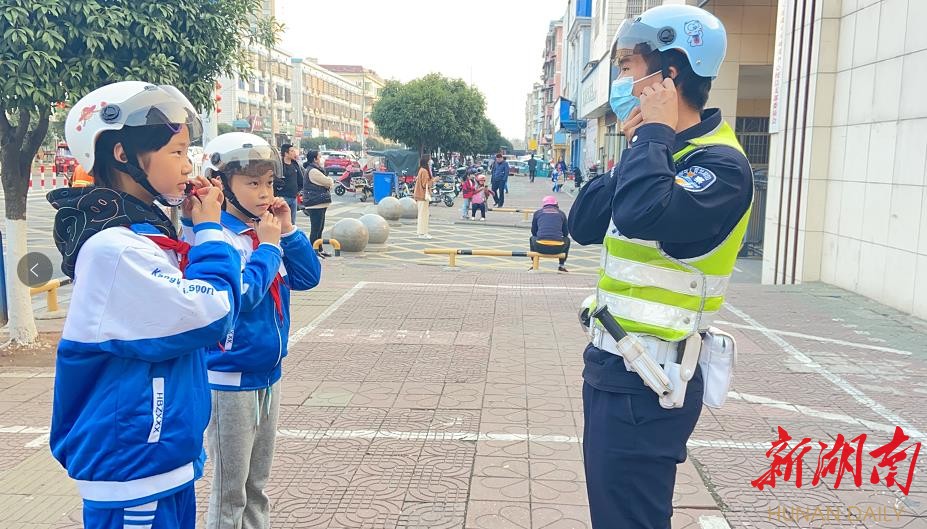 交警和“小记者”向群众演示头盔正确佩戴方式。曹晓艺 摄