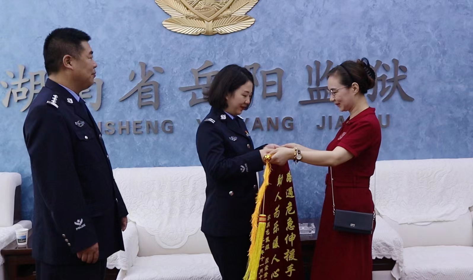 在省岳阳监狱副监狱长李绍元(左)的见证下,小包母亲(右)亲手将锦旗交至谢扬文(中)手中。 在省岳阳监狱副监狱长李绍元(左)的见证下,小包母亲(右)亲手将锦旗交至谢扬文(中)手中。