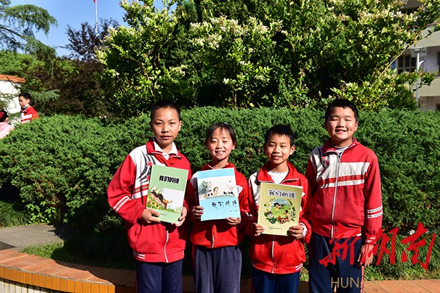 孩子们高兴地展示由李柏霖编辑的《我们的诗》诗集，孩子们的作品刊发在这上面。朱毅 甄叙斐 摄