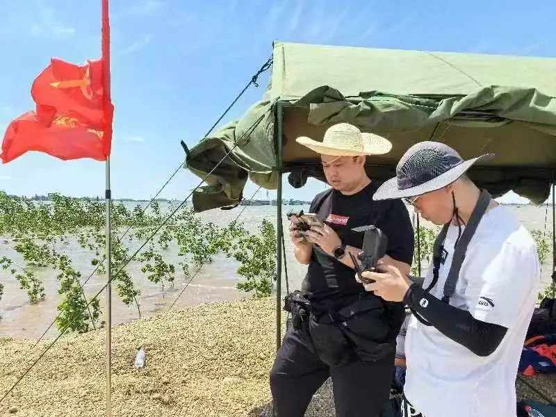 7月7日12时20分，红网记者张必闻、韩佳根离开决口合龙现场，顶着烈日和高温，操控无人机，航拍大堤合龙处。