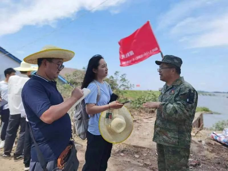 7月7日下午，人民日报记者孙超(左一)、人民网记者吴茜薇(左二)在钱团间堤第二道防线上采访平江县民兵应急连