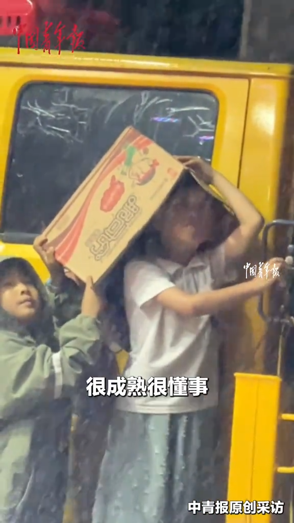 男孩在雨中帮表演杂技的父母调节高度，手紧紧握着机器不松开