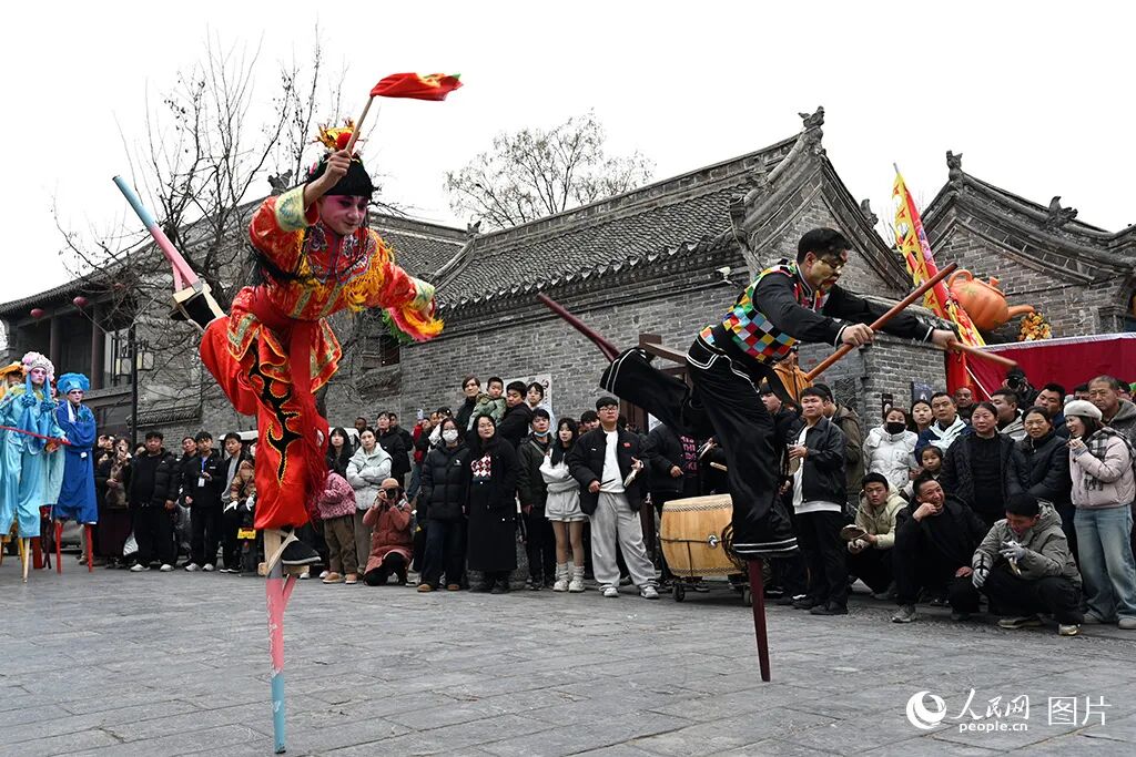 2026年2月10日北方小年，“春满中原·老家河南”主题活动豫北主会场在安阳市滑县启动，游客在道口古镇观看高跷表演。人民网记者 王玉兴摄