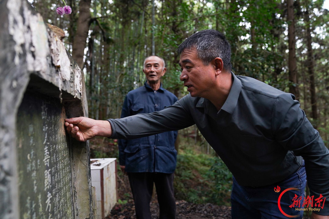 9月1日，全州县安和镇大口岩村，红三十四师一〇一团三营营长李大棋的儿子李得明（左）和孙子李付荣（右）在其墓地打理。湖南日报全媒体记者 唐俊 摄