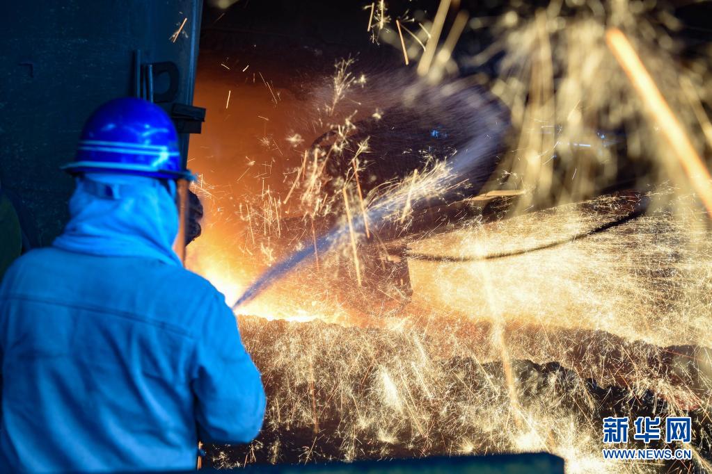 7月24日,工人在首钢水钢公司铁焦事业部四号高炉出铁水时洒水降尘.
