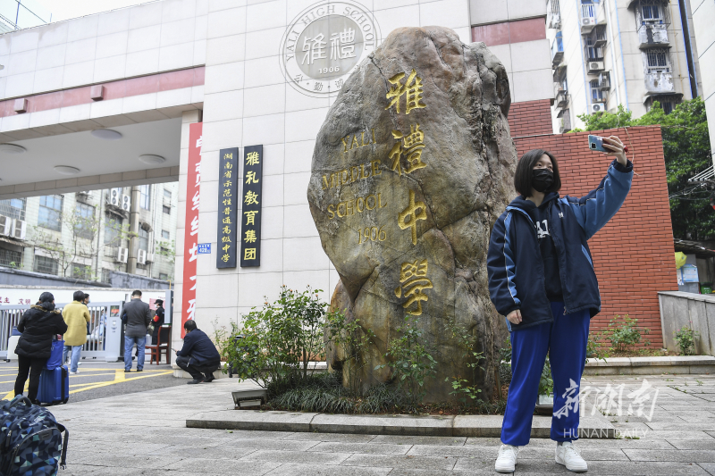 4月17日,長沙市雨花區雅禮中學,一名返校的學生在校門口拍照.