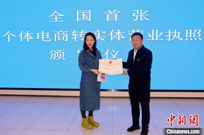 3月23日，个体工商户刘女士领取了变更后的营业执照，成为首家个体网店转变为实体个体工商户的经营者。  中新社记者 张宇 摄